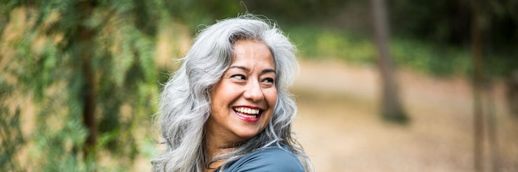 lachende-vrouw-lang-grijs-haar-buiten-750x250